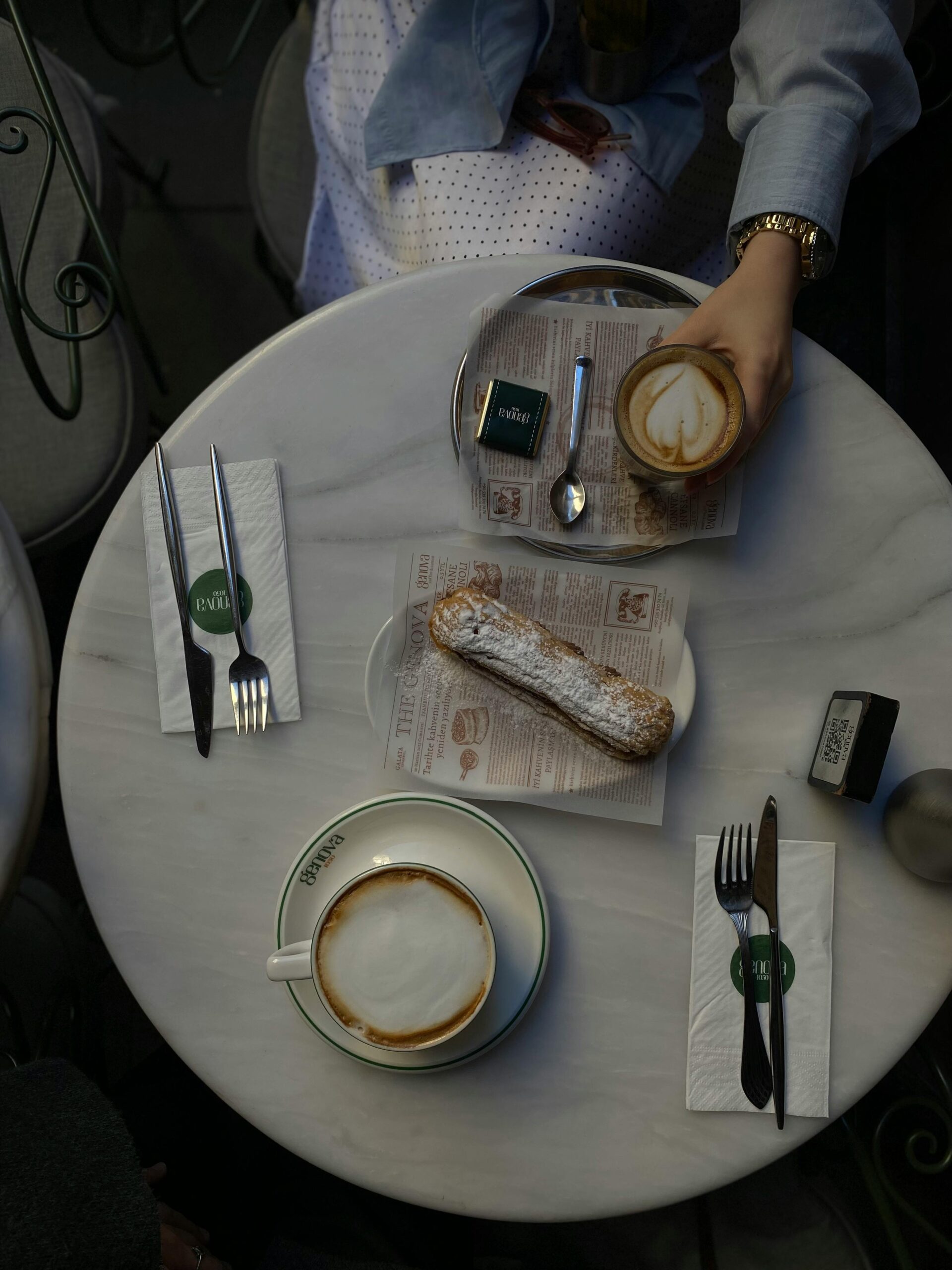 Overhead view of coffee and pastry on a marble cafe table, perfect for breakfast settings.
